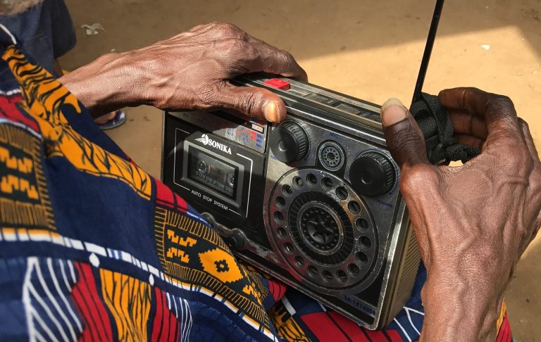 Elderly African woman with radio An elderly African woman listening to an old radio.